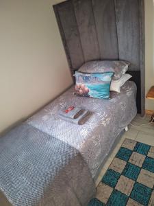 a small bed with a gray bedspread and a pillow at Steijn Apartment 1 in Standerton