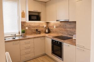 a kitchen with white cabinets and a sink at Apartman Pred polom in Trenčín