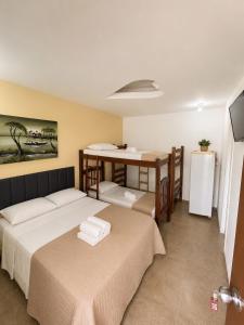 a room with two beds and a table in it at Pousada Recanto Paradise in Porto De Galinhas +14 photos