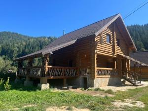 a log cabin with a porch and a balcony at Думанія in Verkhovyna