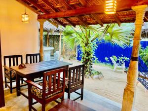 a dining table and chairs under a wooden pergola at Lagoon Hostel in Arugam Bay