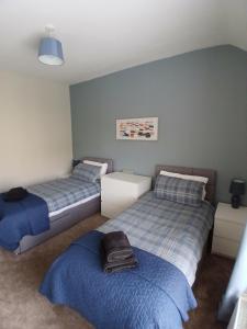 two beds in a room with blue walls at Hilltop Retreat at Banktop in Southowram