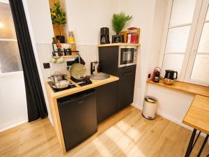 a small kitchen with a sink and a microwave at MRODBNB - Appart Neuf - Aperçu Mer - 25m Plage & Resto - Ciné - Cheminée - Popcorn in Cancale
