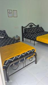 two beds sitting next to each other in a room at ZIRA STAY PENARIK - Ziyad Room in Kampong Ru Sepuloh