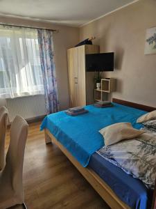 a bedroom with a bed with blue sheets and a television at Duet in Władysławowo +62 photos