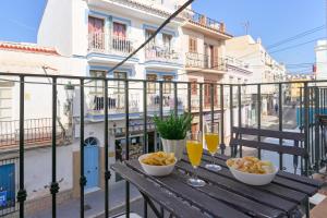 a table with two glasses of wine and snacks on a balcony at Apartamentos Nerjaluna in Nerja
