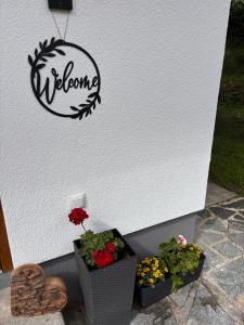 a welcome sign on a wall with two plants at Irmas Ferienhäusl in Längenfeld +30 photos