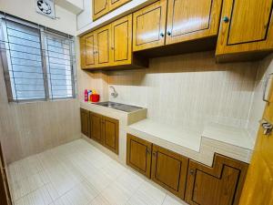 a kitchen with wooden cabinets and a sink at Vacation House a Service Apartment in Cox's Bazar