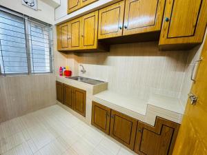 a kitchen with wooden cabinets and a sink at Vacation House a Service Apartment in Cox's Bazar
