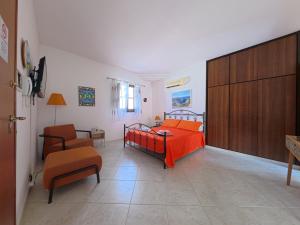 a bedroom with a bed with an orange blanket and a chair at millennium holiday in Castellammare del Golfo