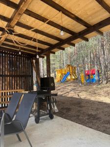 a picnic table and chairs under a pavilion with a playground at Vodice Park, Zlatibor in Vodice