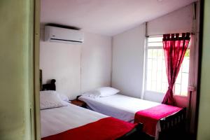 two beds in a small room with a window at La melosa in Girardot