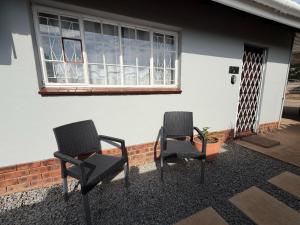 two chairs sitting outside of a house with a window at 47 on Cleland in Pietermaritzburg +4 photos
