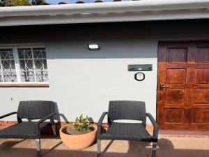 two chairs sitting in front of a building with a door at 47 on Cleland in Pietermaritzburg