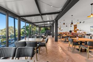 ein Restaurant mit Tischen, Stühlen und Fenstern in der Unterkunft Hotel Vali Dramalj in Crikvenica