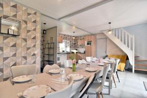 a dining room with a long table and white chairs at Les gites du buisson in Fréhel
