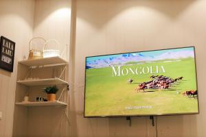 a flat screen tv hanging on a wall with a horse race on it at The ALL-in-ONE LOFT with AIRPORT pickup in Ulaanbaatar