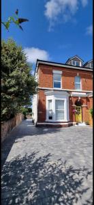 a brick building with a yellow door on a street at 2 bed- walkable train and beach apartment in Crosby