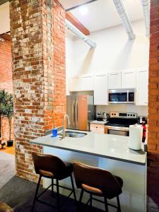 a kitchen with a counter with two chairs and a sink at Historic Federal Hill 1Br Loft apt with onsite Gym and Barbershop in Providence