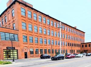 a large brick building with cars parked in front of it at Historic Federal Hill 1Br Loft apt with onsite Gym and Barbershop in Providence