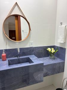 a bathroom sink with a mirror and a vase of flowers at Quarto acolhedor in Aracaju