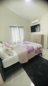 a bedroom with a bed and a dresser and a window at Jamaica Coastal Getaway in Discovery Bay
