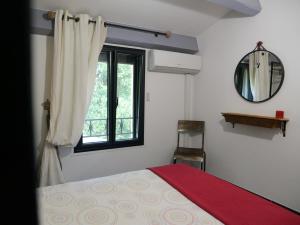 a bedroom with a bed and a window and a mirror at Les Boissèdes in Les Vans