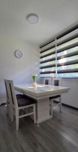 a white table with chairs and a vase on it at S Apartman Vrdnik in Vrdnik