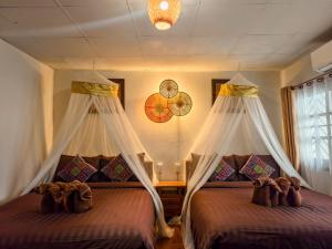 a bedroom with two beds with mosquito nets at Aphilapa House in Chiang Mai