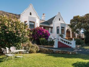 a white house with a table and chairs in the yard at Bonne Esperance, Simon's Town in Simonʼs Town