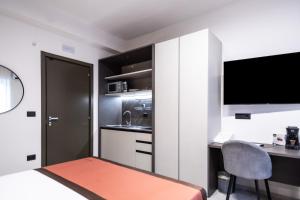 a bedroom with a bed and a desk and a television at Ambrosia Room & Apartment in Rossano