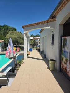 a patio with an umbrella next to a swimming pool at Appartement dans maison en RDC in Nègrepelisse
