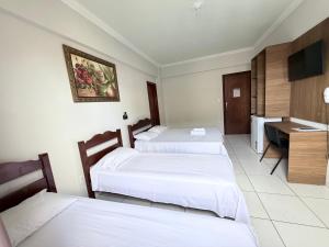 a hotel room with three beds and a desk at Palace Hotel Pôr do Sol in Vitória da Conquista +18 photos