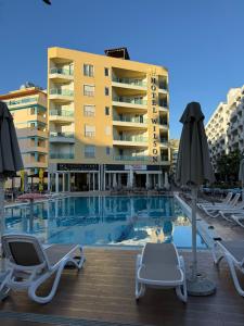 a swimming pool with chairs and umbrellas in front of a building at Sea & Mount apartament in Shëngjin