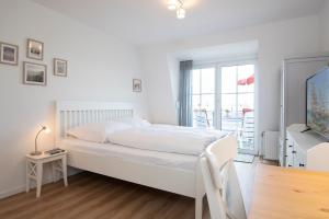a white bedroom with a bed and a balcony at Kleine Meerzeit in Dahme
