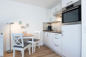 a kitchen with white cabinets and a table with chairs at Kleine Meerzeit in Dahme