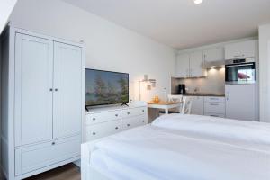 a white bedroom with a bed and a kitchen at Kleine Meerzeit in Dahme +12 photos
