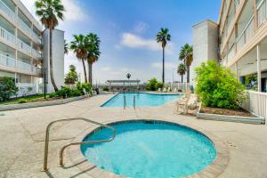 a swimming pool with palm trees and a building at Unwind by the Beach | Pool and Oceanfront View in Corpus Christi
