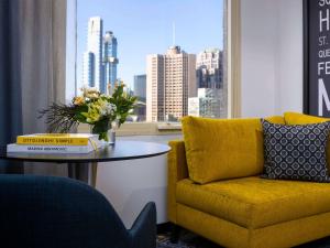 a living room with a yellow couch and a table and a window at Pullman Melbourne City Centre in Melbourne