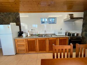 a kitchen with wooden cabinets and a white refrigerator at Retiro dos Cabritos in São Mateus