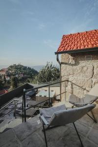 a balcony with two lounge chairs and a roof at Abrigos do Castelo in Carvalho de Rei