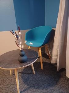 a blue chair sitting next to a table with a vase at Calm Room 10 on pedestrian street Saeby in Sæby