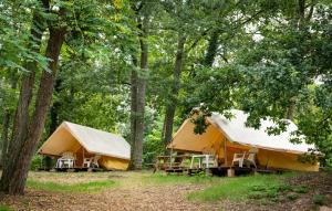 two tents with tables and chairs in the woods at Camping Onlycamp Le Port in Saint-Benoît-sur-Loire