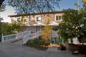 an old stone house with a white fence and trees at Nueva Villa Ignacia in Arriate