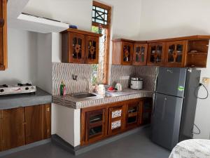 a kitchen with wooden cabinets and a stainless steel refrigerator at Stay Home Arugambay in Arugam Bay