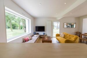 a living room with a yellow couch and a large window at Petite villa cassora in Herm