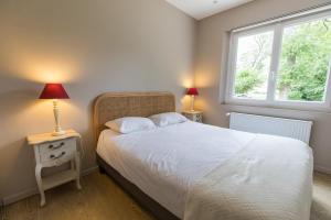 a bedroom with a bed and two lamps and a window at Petite villa cassora in Herm +13 photos