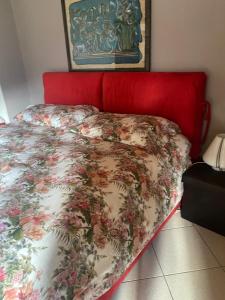 a bed with a red head board with a floral bedspread at casa vacanze LA CA Del Cunfec in Sondrio