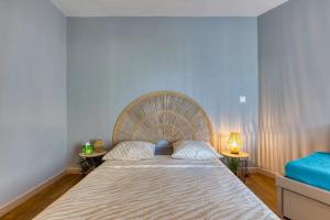 a bedroom with a large bed with a rattan headboard at Le Murmure des palmiers in La Grande Motte