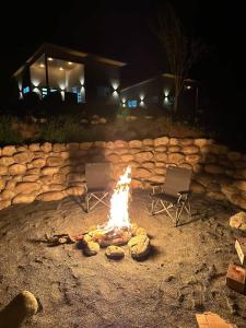 two chairs and a camp fire in the dirt at Muniz Village in Three Rivers